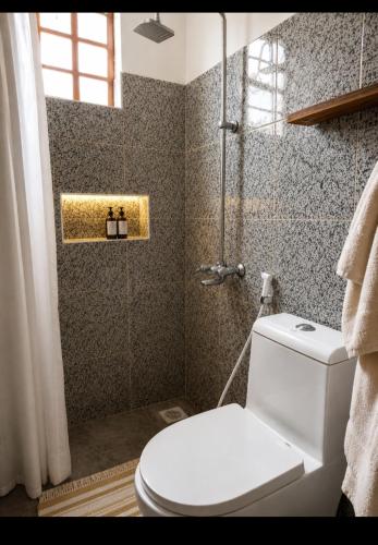 a bathroom with a white toilet and a shower at Kivulini Homes in Arusha