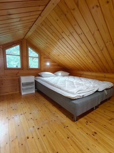 a large bed in a room with a wooden ceiling at Honkaranta Cottage in Jämsä
