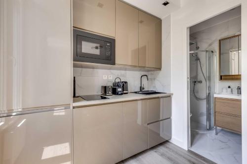 a white kitchen with a sink and a refrigerator at Cozy Studio 4P - Aubervilliers in Aubervilliers