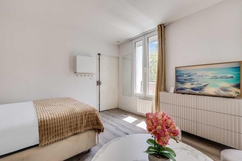 a bedroom with a bed and a table with a vase of flowers at Cozy Studio 4P - Aubervilliers in Aubervilliers