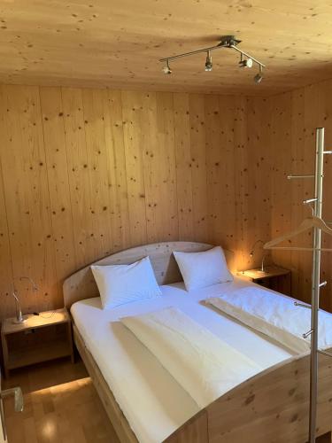 a large bed in a room with wooden walls at 2-Zimmer Ferienwohnung,Parterre,Sitzplatz,Garage in Adelboden