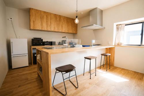 a kitchen with a counter and two stools at 四方宿 in Hokuto