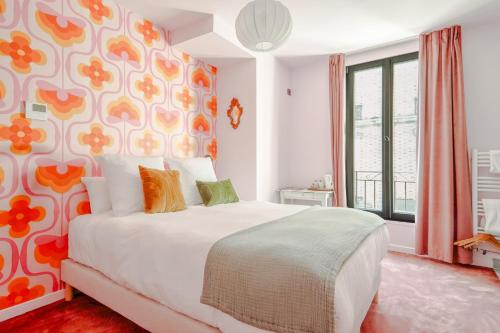 a bedroom with a white bed with a floral patterned wall at Le Charmant Hôtel in Saint-Ouen
