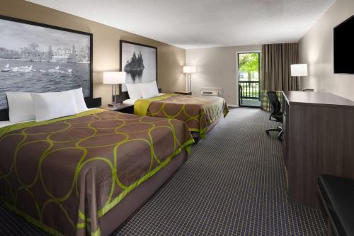 a hotel room with two beds and a flat screen tv at Super 8 by Wyndham Gananoque - Country Squire Resort in Gananoque