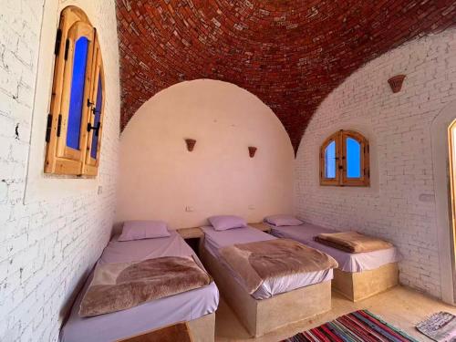a room with three beds and a brick wall at Siwa Nostalgia Ecolodge in Siwa
