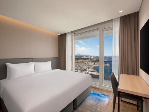 a bedroom with a bed and a desk and a window at Wyndham Goseong Gangwon Hotel in Goseong