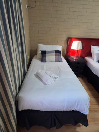 a bedroom with a white bed with towels on it at Ashmont Inn Hotel in Wagga Wagga