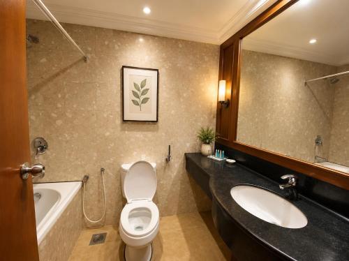 a bathroom with a sink and a toilet and a tub at Oriental Crystal Hotel in Kajang