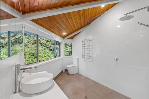 a white bathroom with a wooden ceiling at The Hidden Gem in Tamborine Mountain in Tamborine