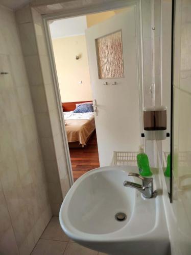a bathroom with a sink and a room with a bed at Hostel Promyk in Iwonicz-Zdrój