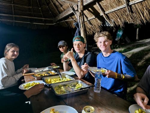 a group of people sitting around a table eating food at Teepo Ke Hillside Jungle Lodge in Ban Mae Sapok Nua