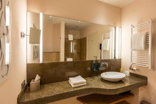 a bathroom with a sink and a large mirror at DoubleTree by Hilton Oradea in Oradea