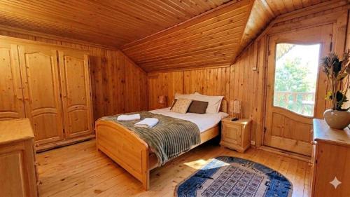 a bedroom with a bed in a wooden room at Cabana de la rau Satic in Sătic