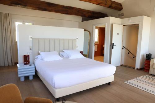 a bedroom with a large white bed and chairs at Hôtel Casa Elena in Erbalunga