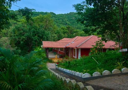 a house with a red roof in a forest at Celestial Heights Coorg by VOYE HOMES with Sunset views-Near to Nagarhole Tiger Reserve in Srimangala