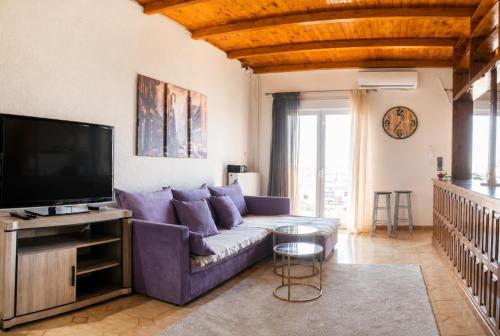 a living room with a purple couch and a tv at Stathohouse - Peaceful Balcony Retreat in Filiatra in Filiatra