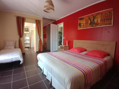 a bedroom with two beds and a red wall at Karibu Normandy-Maasai in Lisieux
