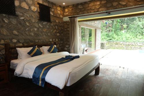 a bedroom with a large bed and a large window at Thimura Resort in Bharatpur