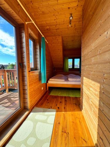 a small room with a bed in a wooden house at Cztery Pory Roku in Sarbinowo