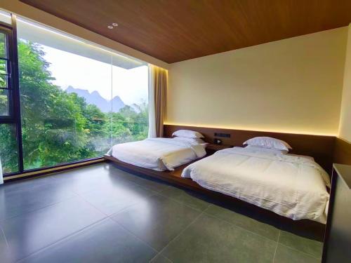 two beds in a room with a large window at Yipin Noble Residence in Xinxu