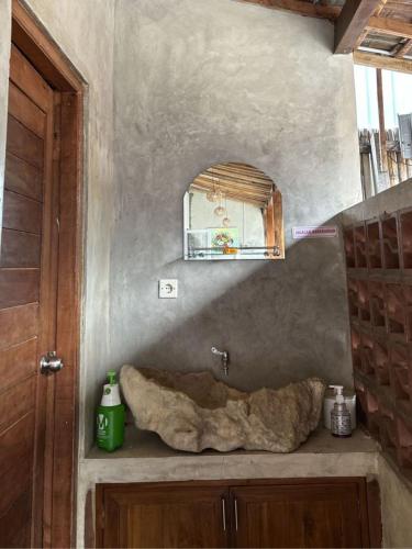 a bathroom with a stone sink and a mirror at Homestay IDR Bali in Jimbaran