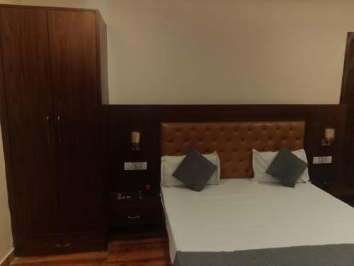 a bedroom with a large bed with white sheets and blue pillows at Hotel Harmony in Kharar