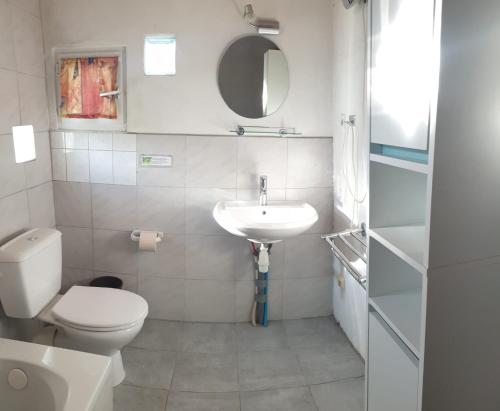a white bathroom with a toilet and a sink at 487 Rue des Grappins in Bouhans