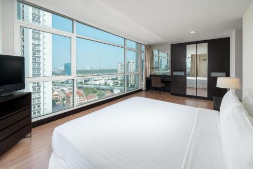 a bedroom with a large white bed and large windows at The Narathiwas Hotel & Residence Sathorn Bangkok in Bangkok