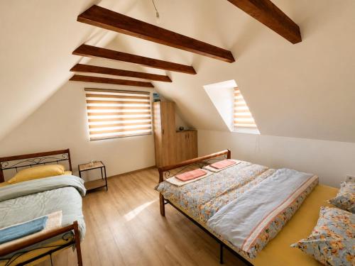 a attic bedroom with two beds and two windows at Lipovo Mountain House in Kolašin