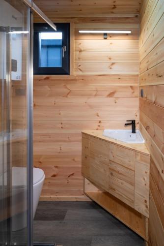 a bathroom with wooden walls and a sink and a shower at Lala Camp in Vama Buzăului