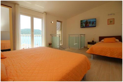 a bedroom with an orange bed and a large window at Apartment Karmela in Primošten