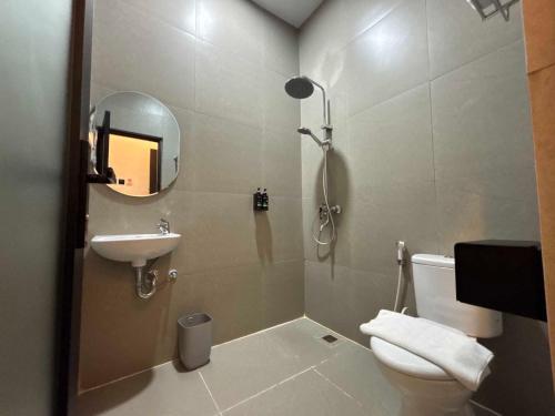 a bathroom with a toilet and a sink and a mirror at The Quadrant Hotel Ocarina Batam in Batam Center