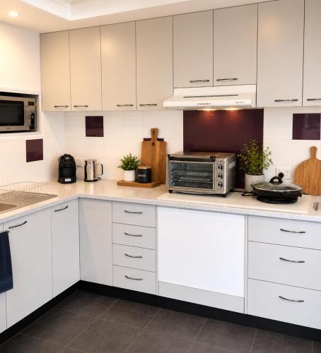 a kitchen with white cabinets and a microwave at Golfside Getaway by Ready Set Stay in Rosebud