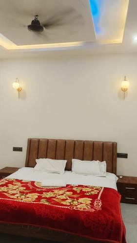 a bedroom with a large bed with a red blanket at Kanha Hotel in Kānpur