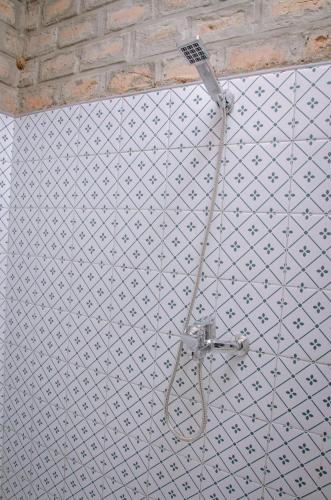a white tiled wall with a shower in a room at Buvi Camp in Buvi