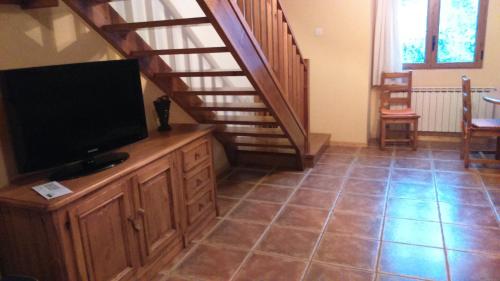 sala de estar con TV y escalera en Duplex Calle El Tillo, en Escarrilla