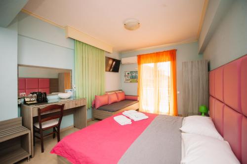 ein Schlafzimmer mit einem rosa Bett, einem Schreibtisch und einem Waschbecken in der Unterkunft Hotel White Rose Beach in Olympiakí Aktí