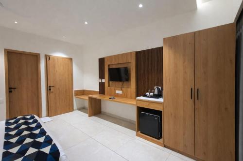 a kitchen with wooden cabinets and a tv in it at Hotel Premji, Dwarka in Dwarka