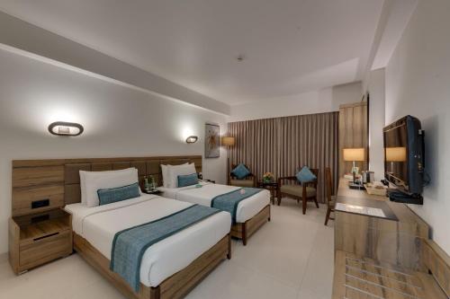 a hotel room with two beds and a television at Hotel Suba International Sahar Road Mumbai in Mumbai