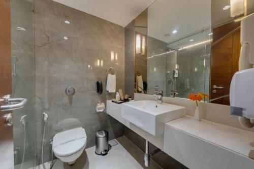 a bathroom with a white toilet and a sink at Hotel Suba International Sahar Road Mumbai in Mumbai