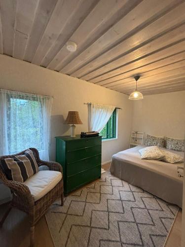 a bedroom with a bed and a chair and a window at En mysig liten Stuga nära naturen och havet in Västlax