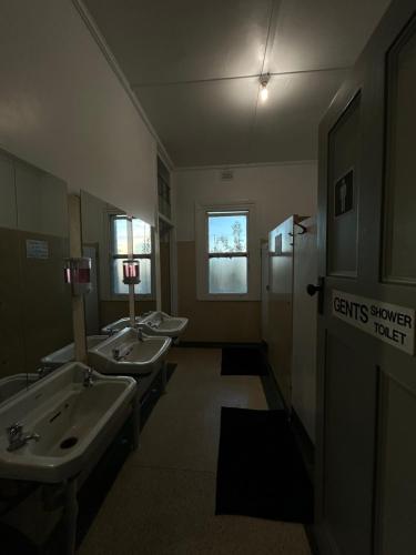 a bathroom with three sinks and a row of urinals at Tailem Bend Hotel in Tailem Bend