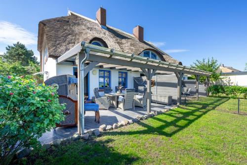 a house with a pergola and a table and chairs at Reethaus Zickersche Berge - WG 02 mit Kamin und Terrasse in Gager