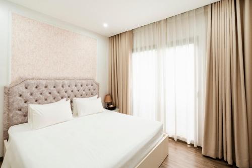 a bedroom with a white bed and a large window at The Serenity Hanoi in Hanoi