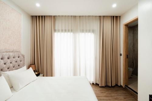 a bedroom with a white bed and a window at The Serenity Hanoi in Hanoi