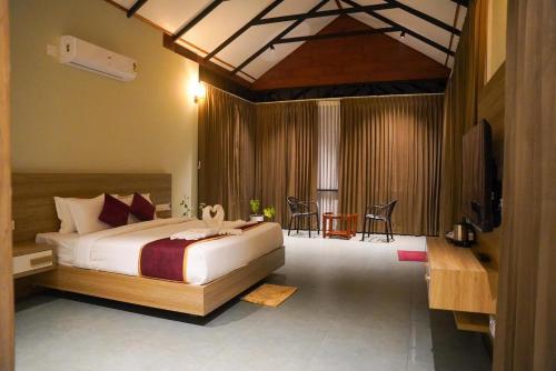 a bedroom with a bed and a television in it at Skyleaf Resort in Meenangadi