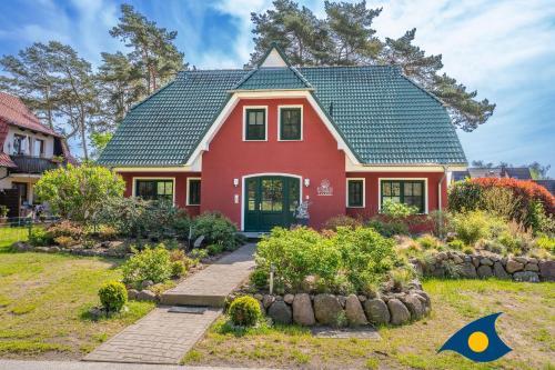 a red house with a green roof at Fraeulein Loddin Whg_ Ole in Kölpinsee