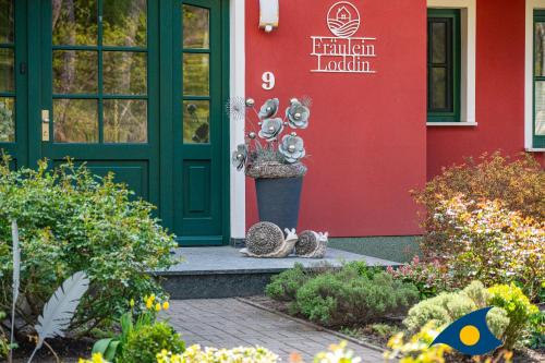 two cats sitting outside of a building with a door at Fraeulein Loddin Whg_ Ole in Kölpinsee