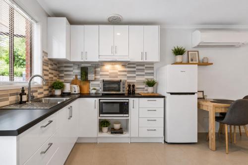 a kitchen with white cabinets and a table and a refrigerator at Golfside Getaway 2 by Ready Set Stay in Rosebud