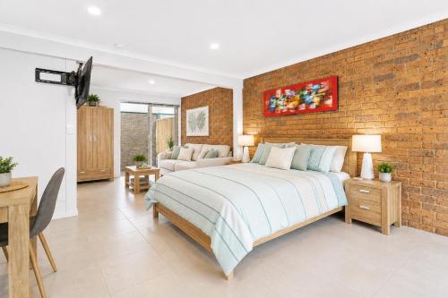 a bedroom with a bed and a brick wall at Golfside Getaway 2 by Ready Set Stay in Rosebud